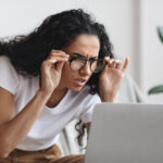 Presbyopia woman straining her eyes looking at a computer screen