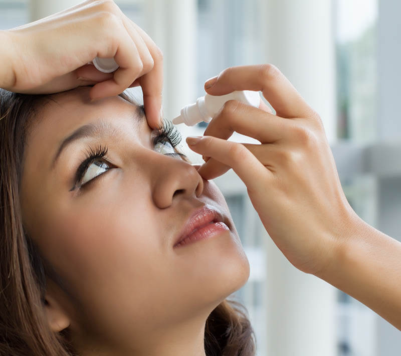 Woman putting eye drops into her eyes