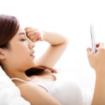 Woman in bed looking at her phone